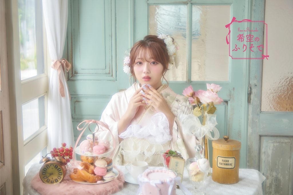 「淡いピンクとアイボリーの振袖を着た希空(のあ)が、華やかな牡丹柄の淡色振袖を清楚に着こなしている全身写真。」