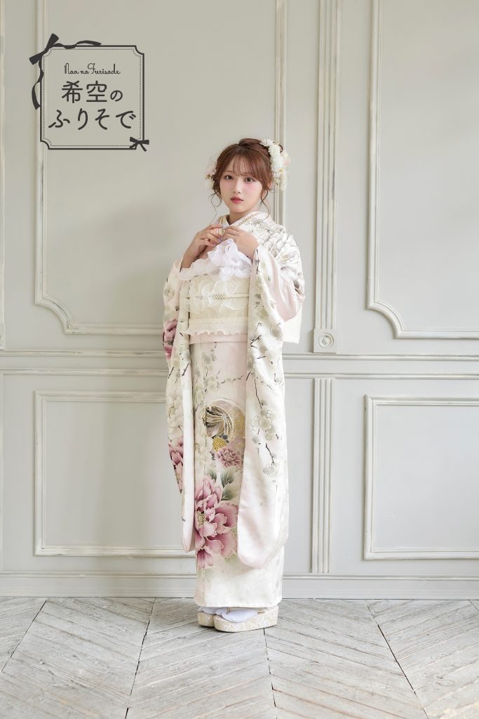 「淡いピンクとアイボリーの振袖を着た希空(のあ)が、華やかな牡丹柄の淡色振袖を清楚に着こなしている全身写真。」