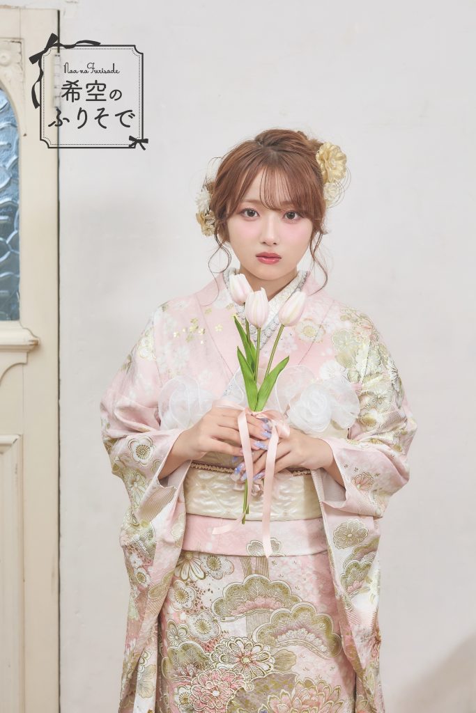 「淡いピンクに金彩が施されたガーリーな振袖を着た希空(のあ)が、クラシカルに立ち姿を見せている写真。」