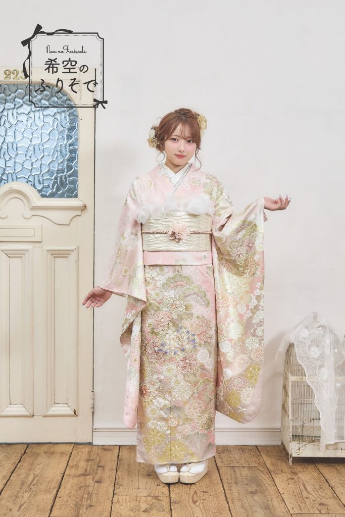 「淡いピンクに金彩が施されたガーリーな振袖を着た希空(のあ)が、クラシカルに立ち姿を見せている写真。」