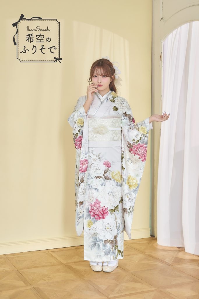 「白地に淡いピンクや黄色の花柄が描かれた振袖を着た希空(のあ)が、清楚で柔らかな雰囲気でポーズをとる写真。」