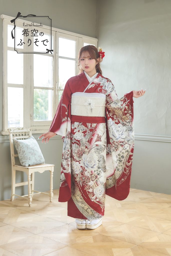 「深紅と白の花柄が華やかな振袖を着た希空(のあ)が、モードで大人っぽいスタイリングで佇む全身写真。」