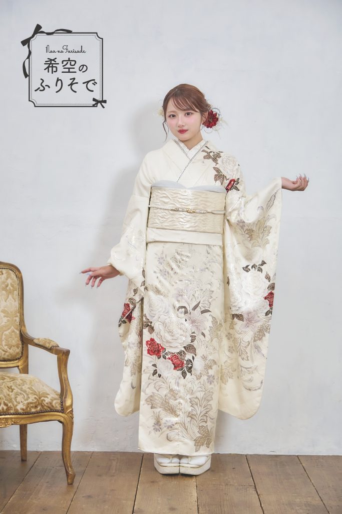 「白地に深紅の花柄振袖を着た希空(のあ)が、赤い差し色と花柄を引き立てる上品コーデで立っている写真。」
