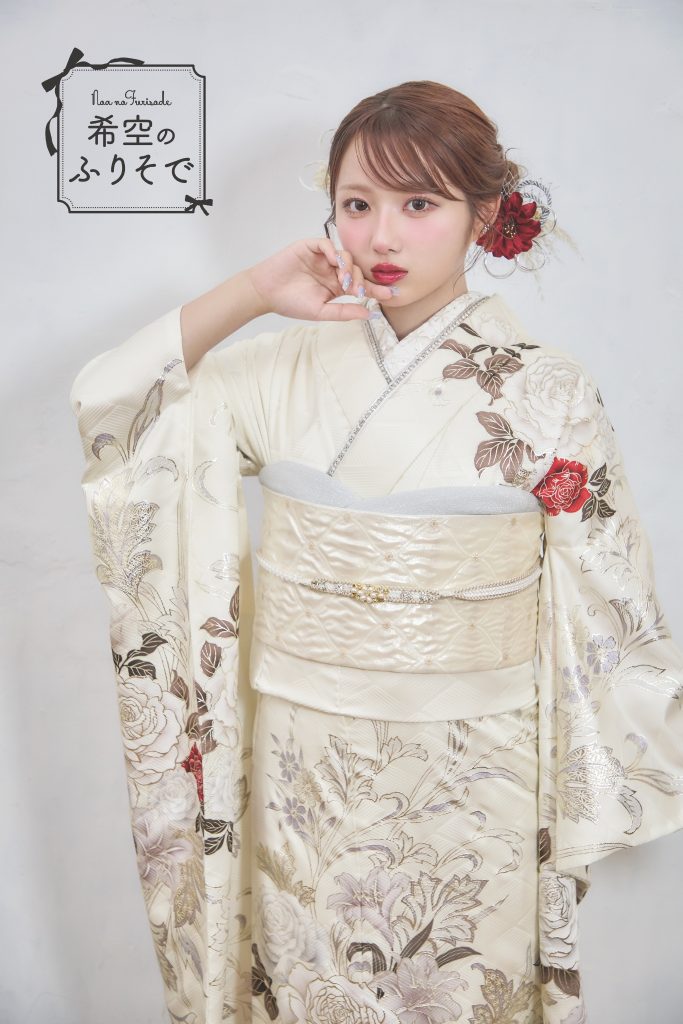 「白地に深紅の花柄振袖を着た希空(のあ)が、赤い差し色と花柄を引き立てる上品コーデで立っている写真。」