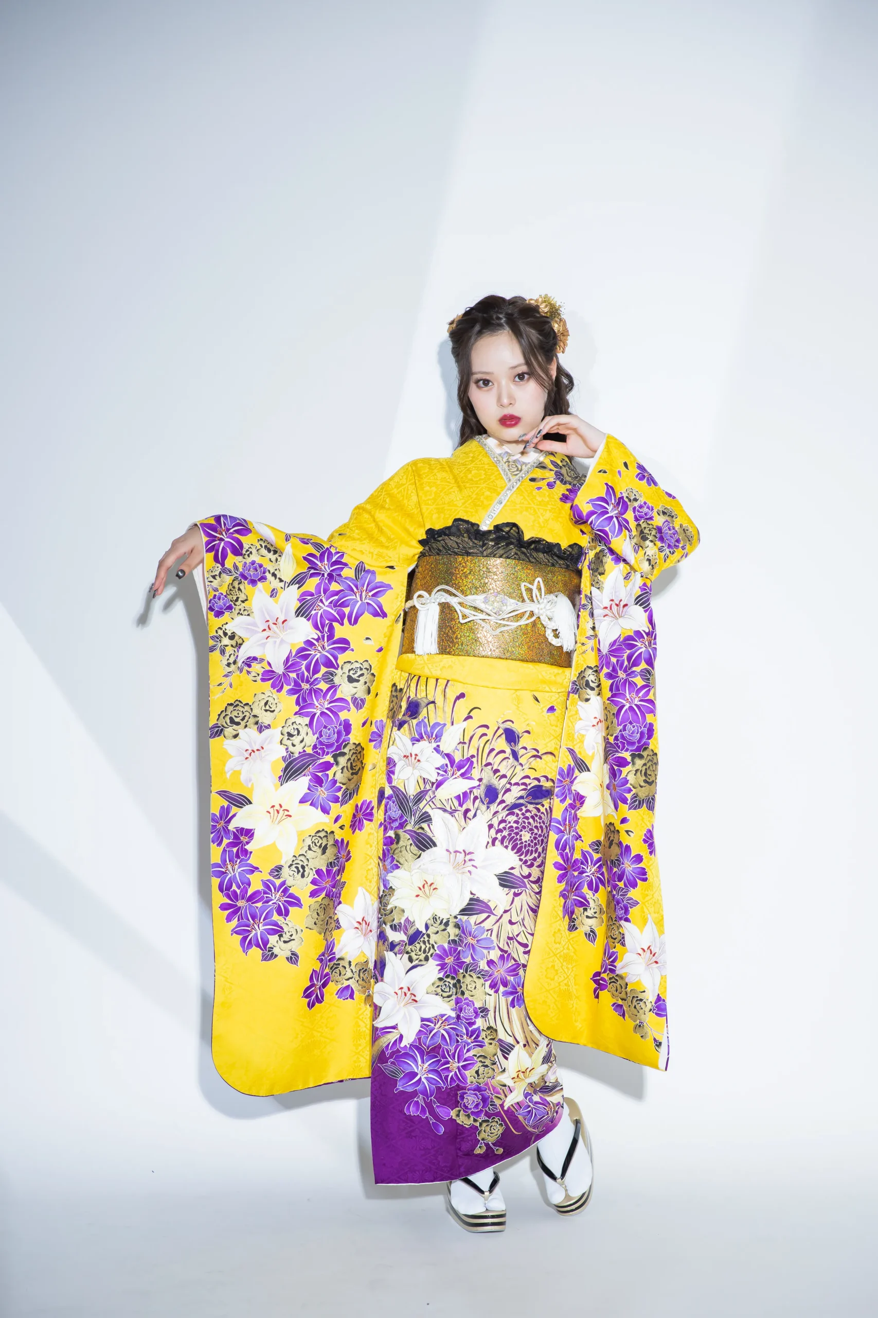 黄色地に紫と白の百合柄が映える華やかな古典振袖を着用した女性の全身スタジオ写真。成人式振袖レンタルPLUM（プラム）岐阜・一宮対応