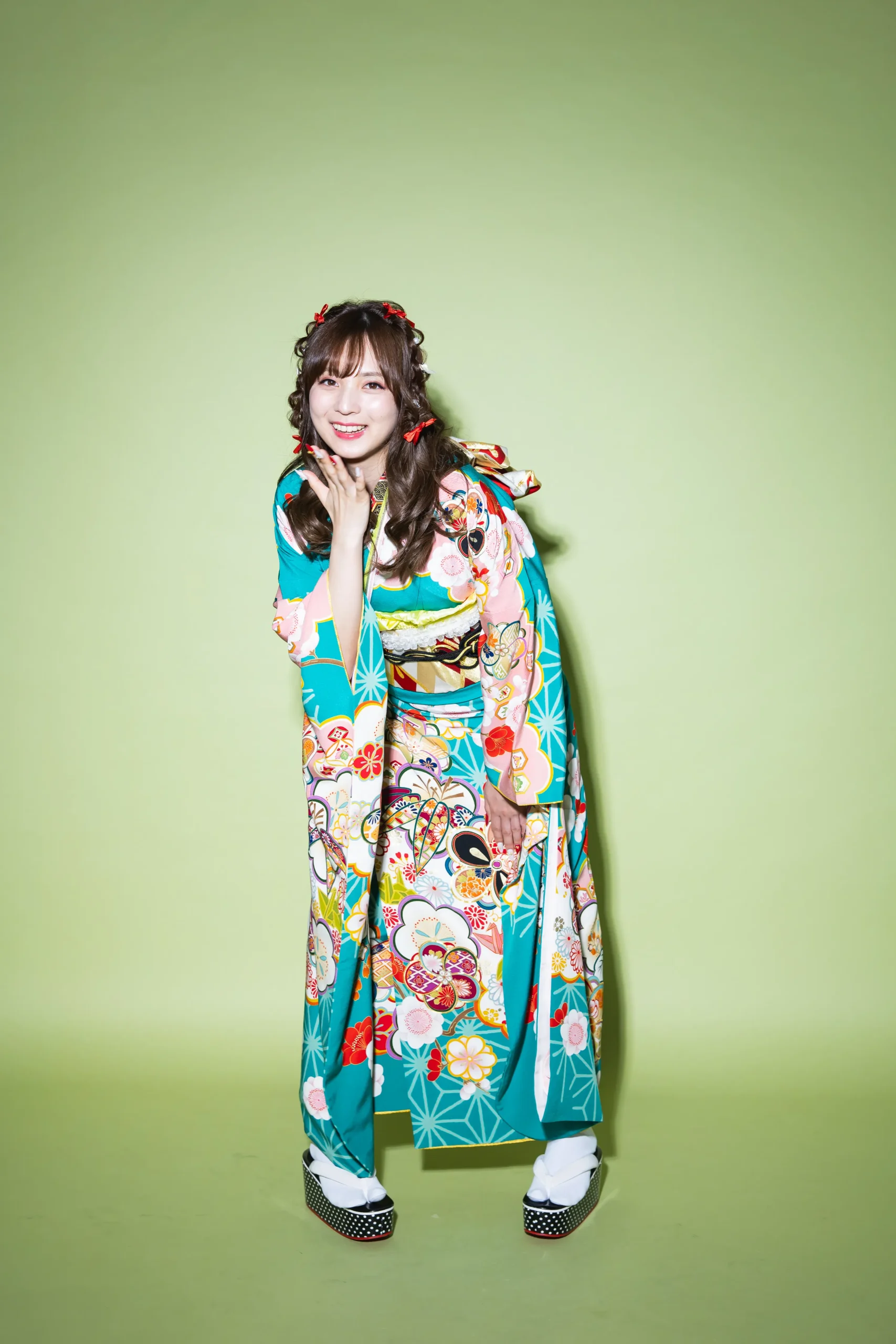 エメラルドグリーン地にカラフルな古典柄が描かれたポップで可愛い振袖を着用した女性の全身スタジオ写真。成人式振袖レンタルPLUM（プラム）岐阜・一宮対応