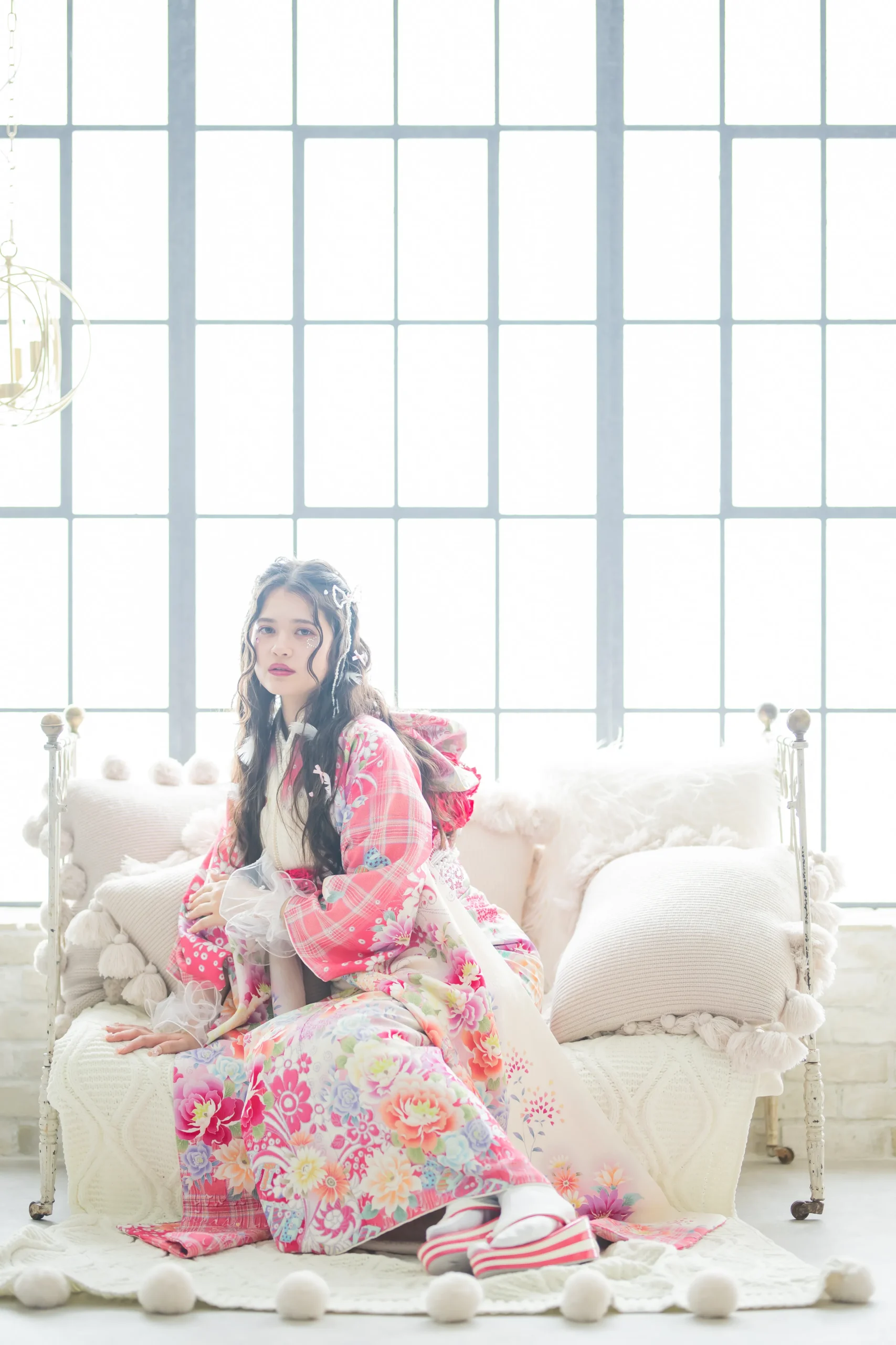 白地にピンクを基調とした花柄とロゴデザインが可愛いガーリー振袖を着用した女性の全身スタジオ写真。成人式振袖レンタルPLUM（プラム）岐阜・一宮対応