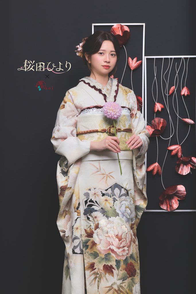 桜田ひより着用の白地振袖。生成りカラーに牡丹や花柄が華やかに描かれた成人式向け振袖。黒背景とアートフラワー装飾で上品かつ写真映えする振袖コーディネート。